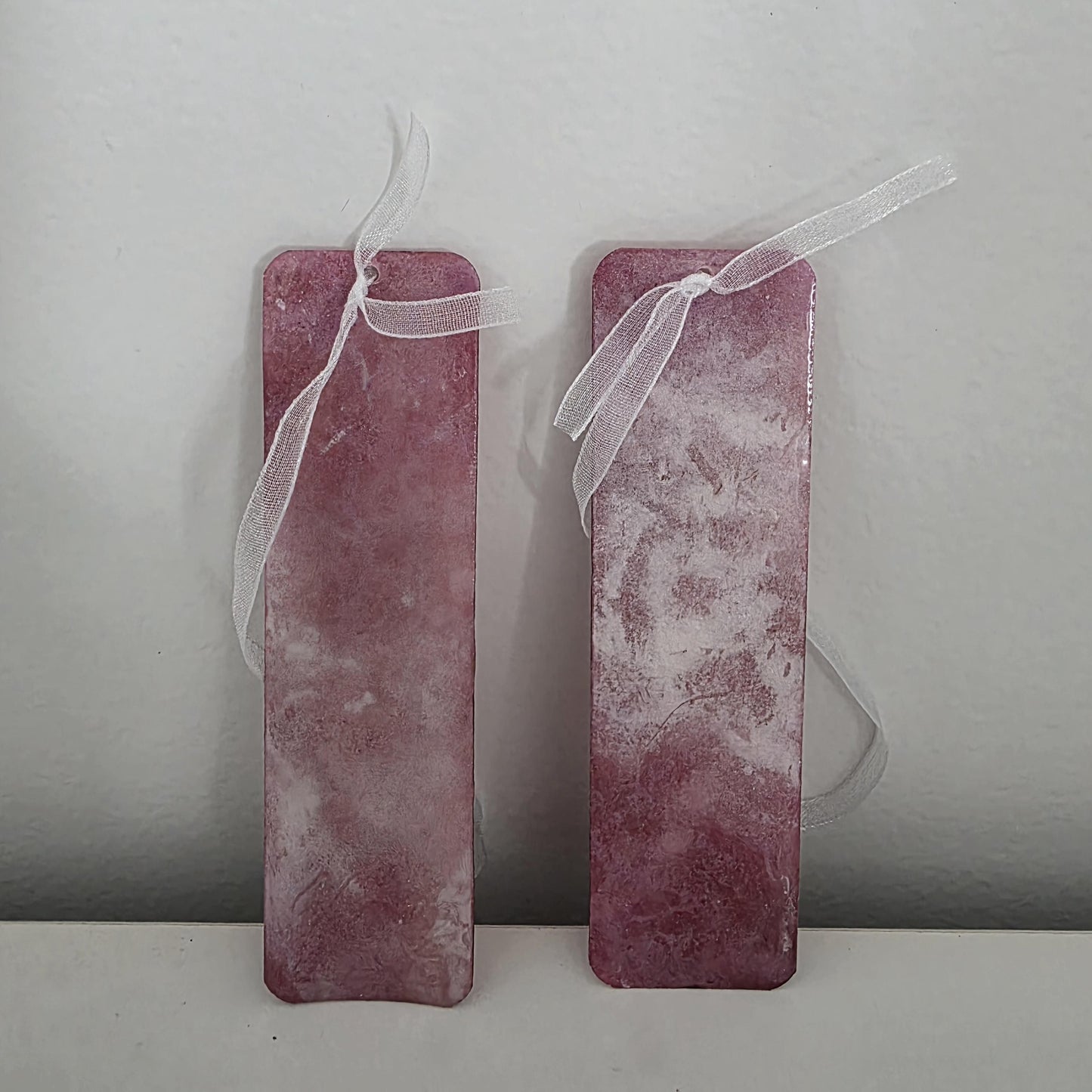 Close-up of terracotta and blush pink bookmarks highlighting the glass-like durability of the UV resin coating and delicate ribbon detail