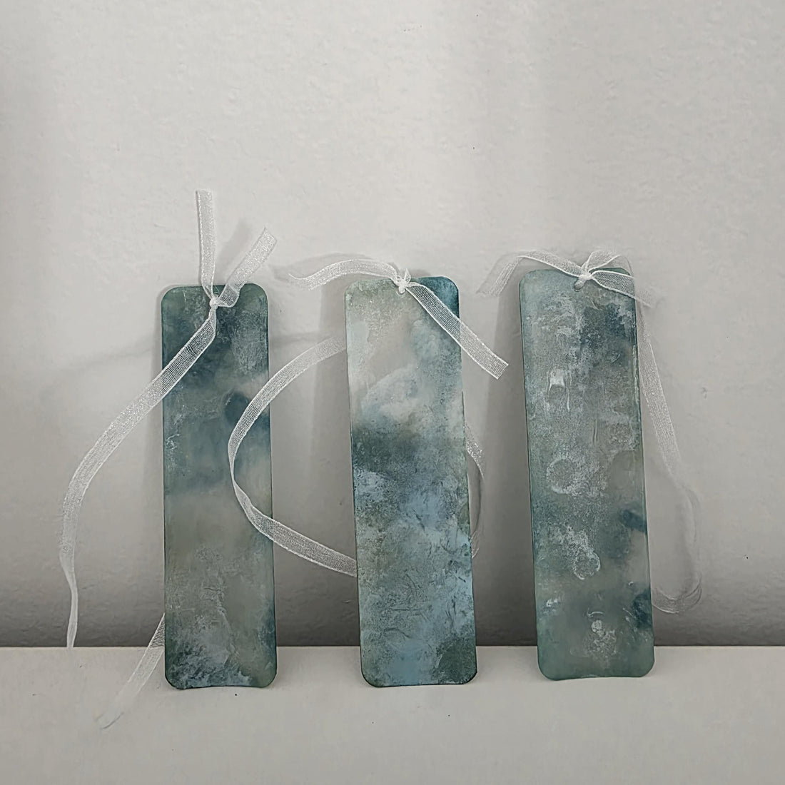 Set of three soft teal and seafoam green alcohol ink bookmarks with delicate white ribbons