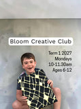 A young boy holding a black and gold textured art piece during a Breathe & Bloom Design creative studio session.