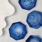 Top-down view of four blue resin and white eco-casting powder coasters showing abstract marble patterns.