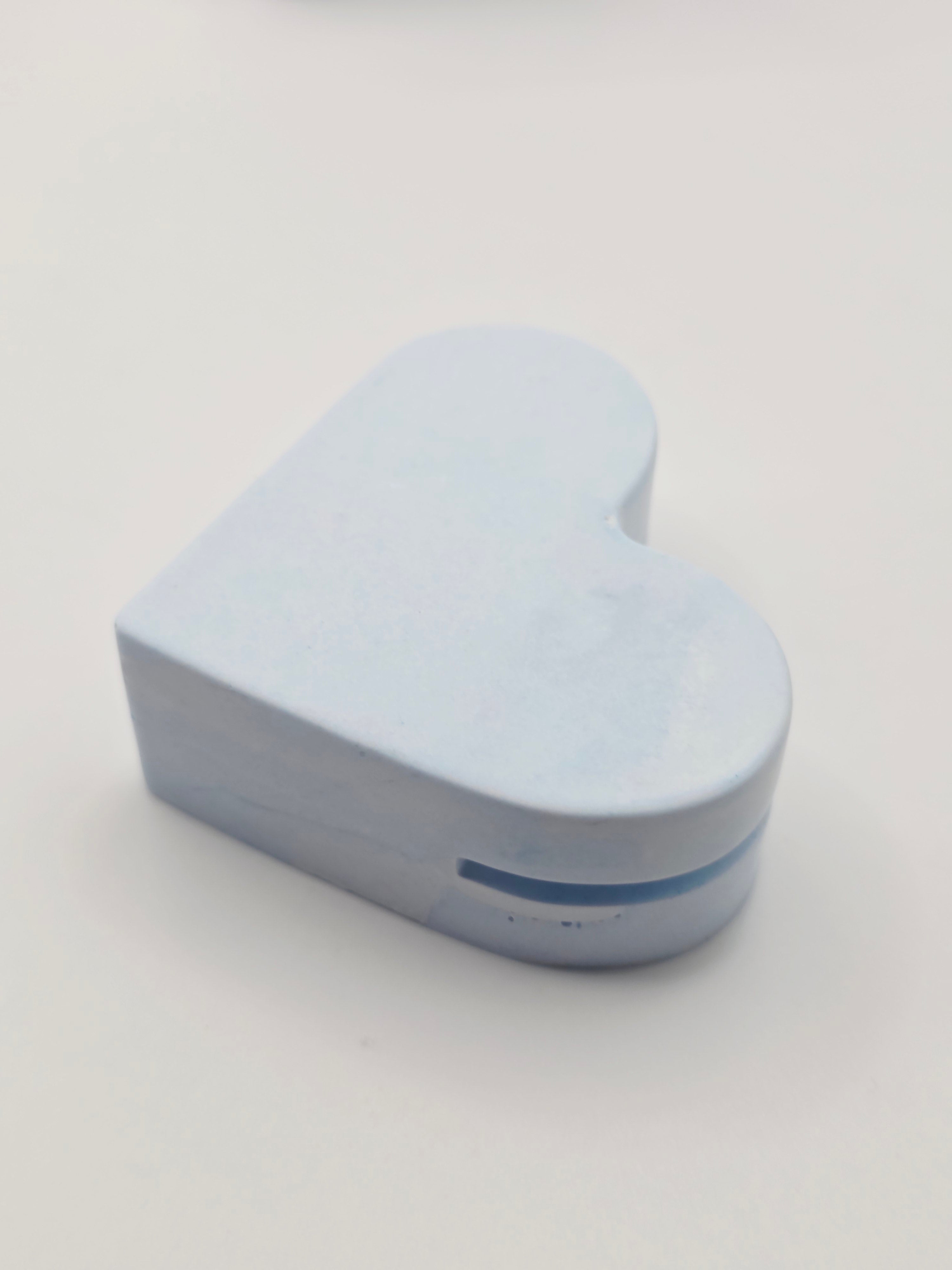 Close-up of a sky blue eco-friendly stone heart card holder with a hand-written name card for wedding table seating arrangements.