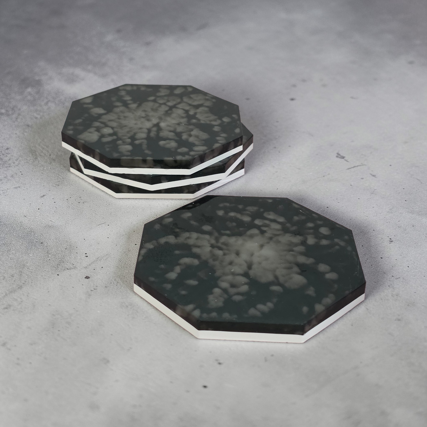 Octagonal black and white drinkware coasters on a gray surface