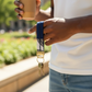A person holding a coffee cup with a navy blue fabric wristlet keychain looped around their finger.