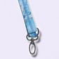 Close-up of silver swivel hook and D-ring hardware attached to a light blue marble fabric lanyard with reinforced stitching.