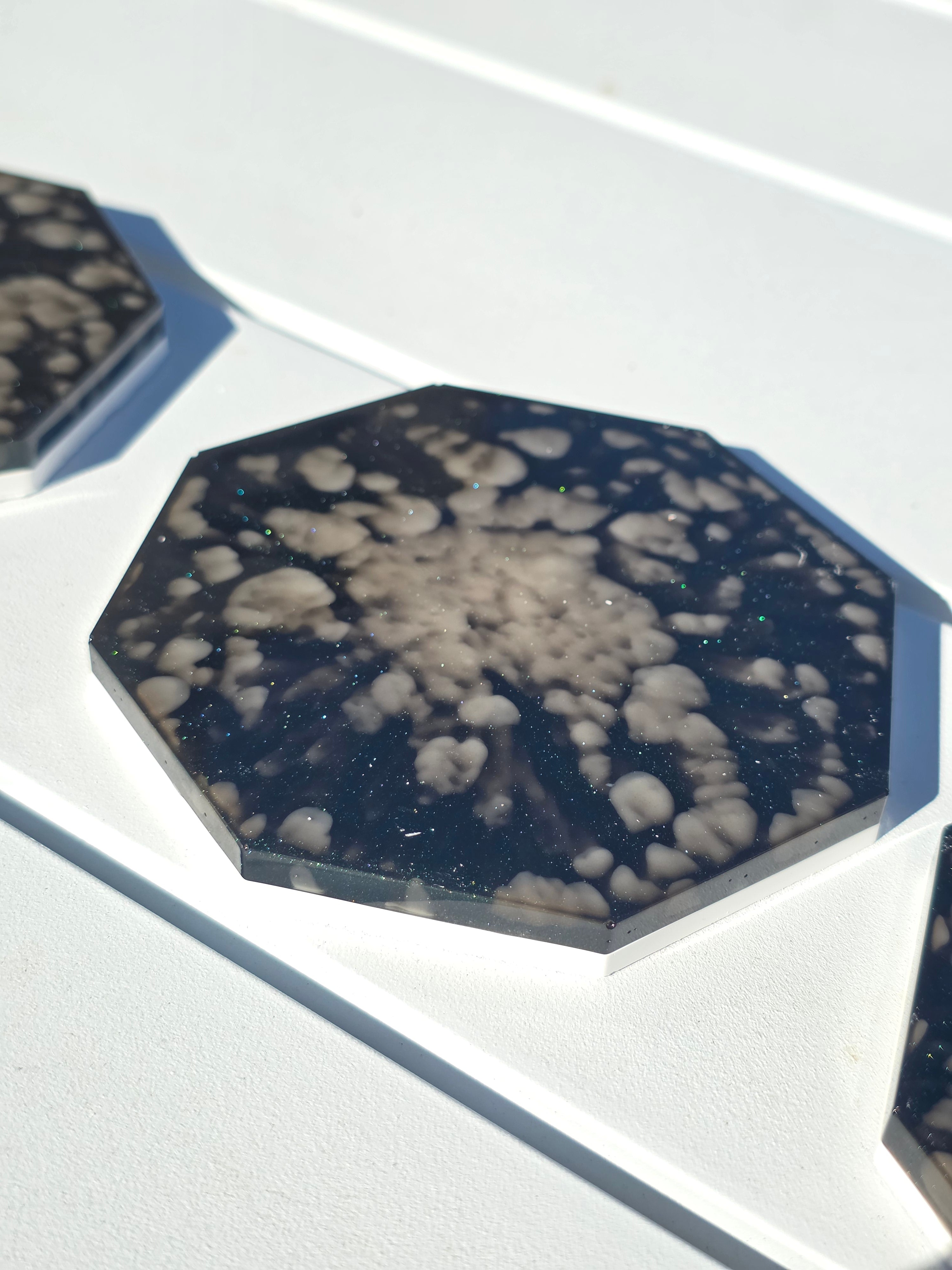 Octagonal eco-stone and resin coasters with black and white pattern on a light gray background