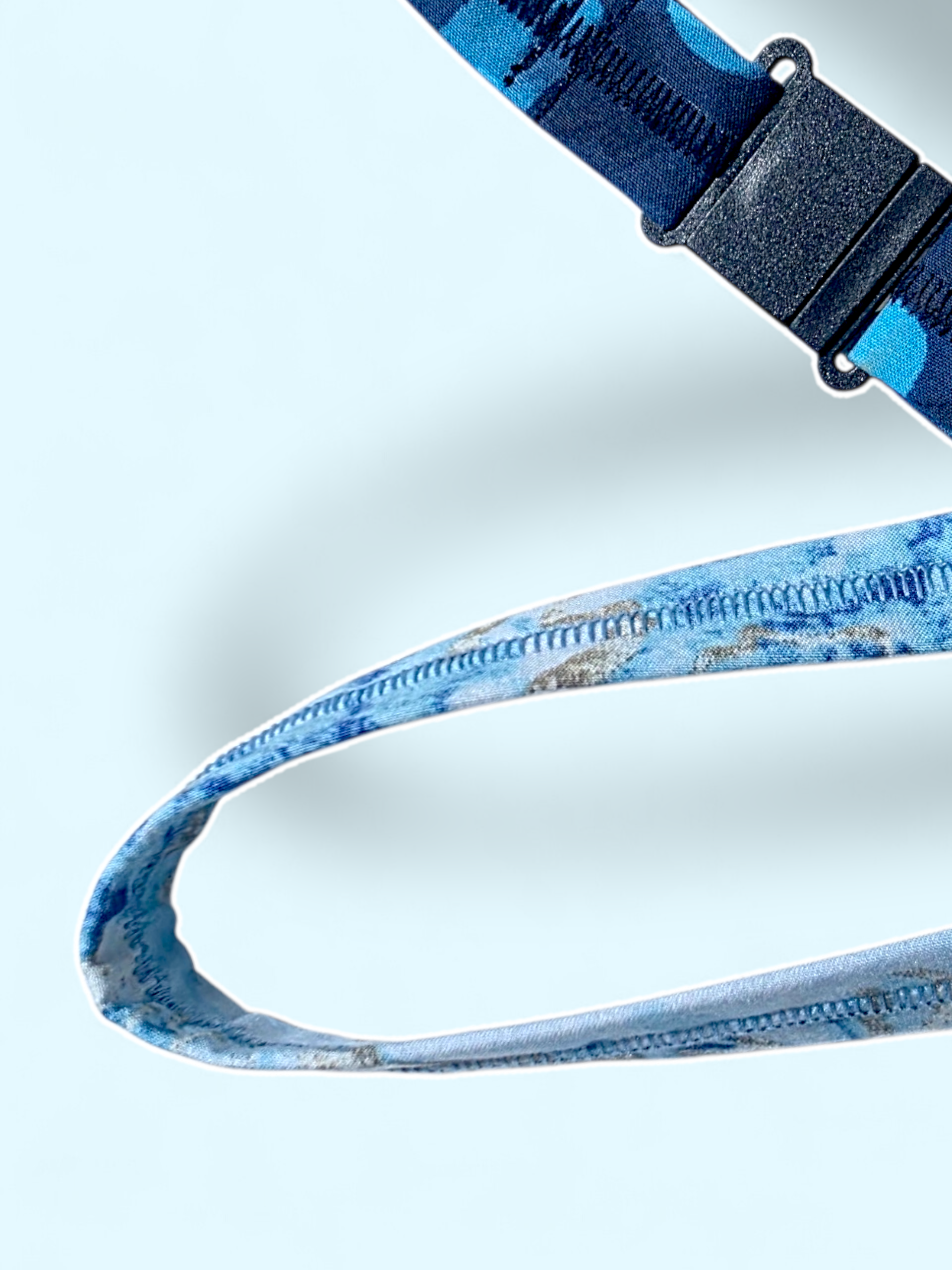 Close-up of a black plastic quick-release safety breakaway clasp on a dark blue patterned lanyard.