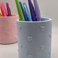 Blue stationery cup with colorful pens on a light gray background