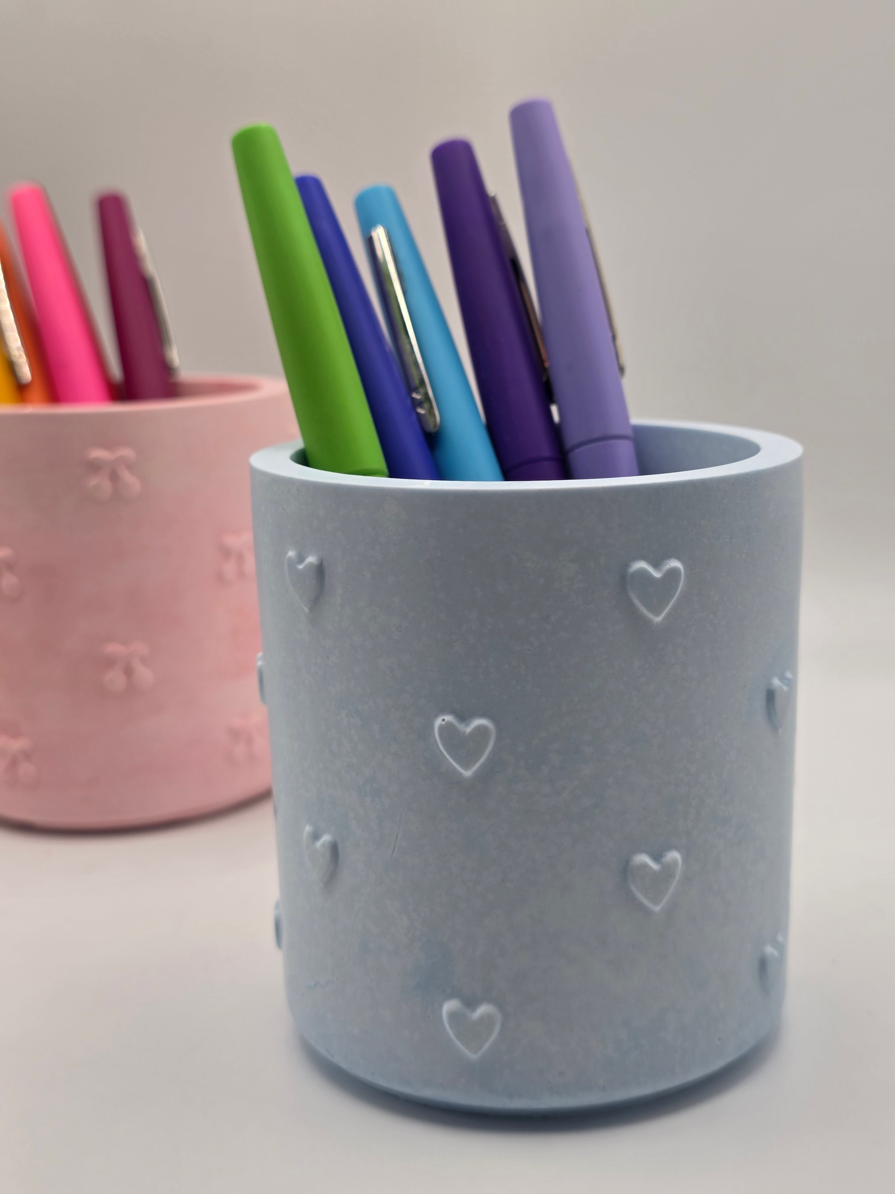 Blue stationery cup with colorful pens on a light gray background