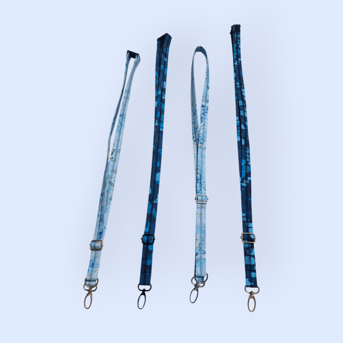 A group of four handmade fabric lanyards in light blue marble and dark blue patterns against a light background.