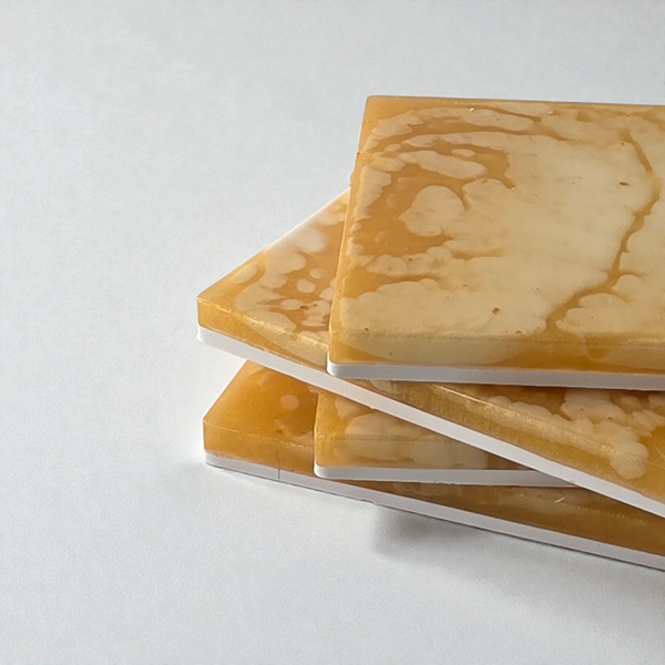 A stack of square honey-colored coasters tied with a rustic twine bow on a wooden coffee table next to a glass of water.