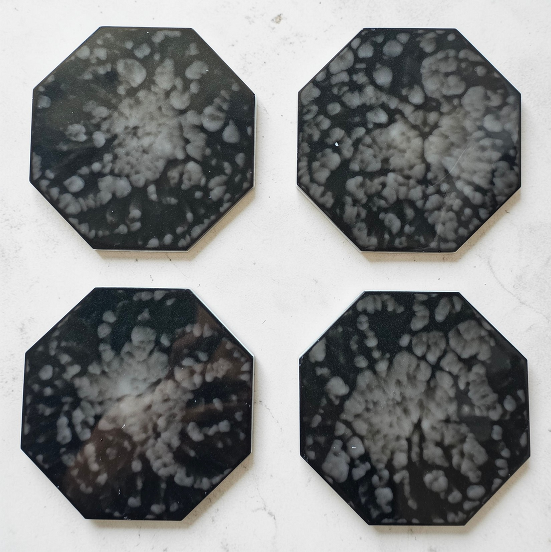 Four octagonal black and white patterned drink coasters on a light background