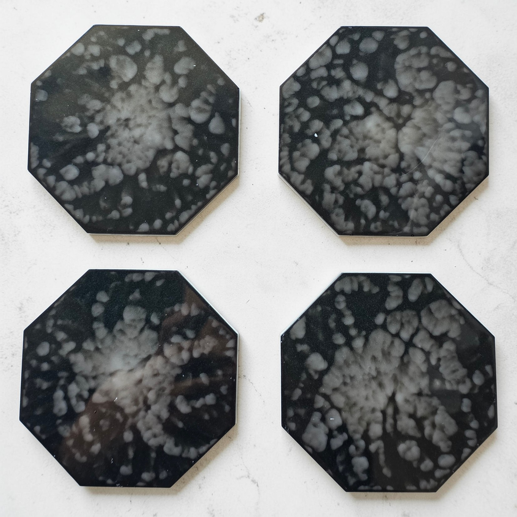 Four octagonal black and white patterned drink coasters on a light background